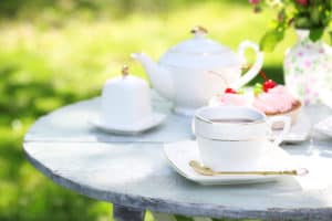Coffee table with teacups and tasty cakes in garden